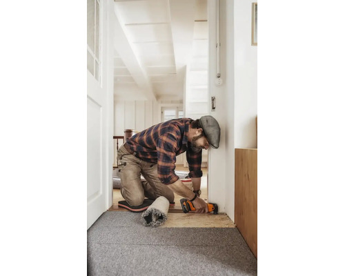 Handwerker kürzt einen Türrahmen mit einem Multifunktionswerkzeug in einer hellen Wohnumgebung.