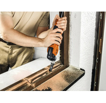 Handwerker verwendet ein Multifunktionswerkzeug zum Bearbeiten eines Fensterrahmens aus Holz.