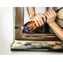 Handwerker verwendet ein elektrisches Multifunktionswerkzeug mit Starlock Max Aufnahme zum Schneiden an einem Holzfensterrahmen.