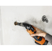 Ein akkubetriebenes Multifunktionswerkzeug mit Starlock Plus Aufnahme schneidet ein Metallrohr aus einer Wand.