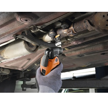 Multifunktionswerkzeug beim Einsatz am Auto unter dem Fahrzeugboden zum Schneiden von Metallteilen.