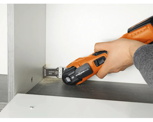 Hand beim Einsatz eines oszillierenden Multifunktionswerkzeugs mit Starlock Plus Aufnahme zum bündigen Sägen an einem Möbelstück.