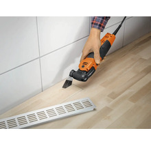 Eine Person schneidet mit einem elektrischen Multifunktionswerkzeug einen Ausschnitt in eine Arbeitsplatte aus Holz.