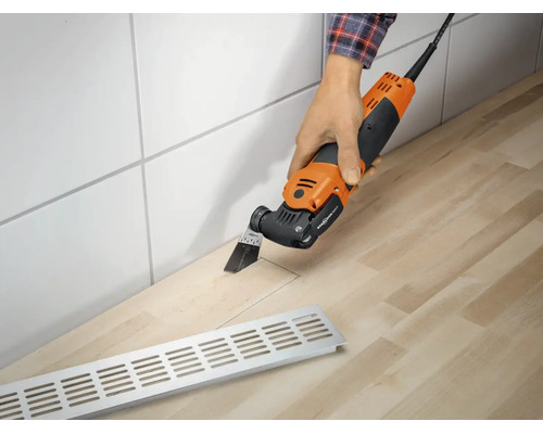 Eine Person schneidet mit einem elektrischen Multifunktionswerkzeug einen Ausschnitt in eine Arbeitsplatte aus Holz.
