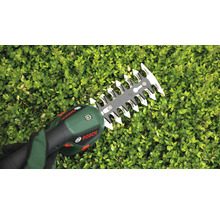Eine Bosch Akku Heckenschere schneidet eine Hecke im Garten.