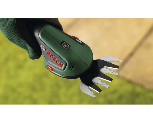 Eine handgehaltene Bosch Akku Grasschere mit Ladestatusanzeige in einer mit Arbeitshandschuhen bekleideten Hand.