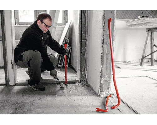 Ein Handwerker nutzt ein Brecheisen bei Renovierungsarbeiten in einem Innenraum.