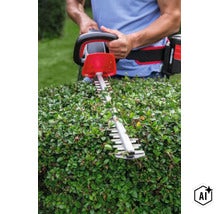 Person verwendet eine Akku Heckenschere zum Schneiden einer Hecke im Garten. (Image AI modified or generated)