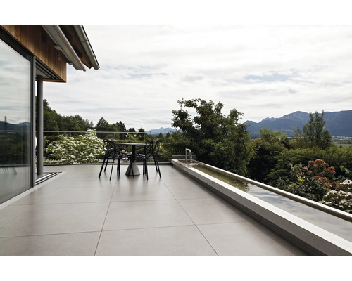 Moderne Terrasse mit großen Bodenfliesen, Sitzgruppe und einem langgestreckten Wasserbecken mit Blick auf die Alpen.