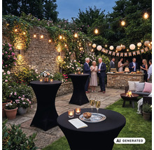 Gartenfeier bei Abenddämmerung mit Stehtischen, Lichterketten, Lampions, Blumen, Steinmauer und Gästen in einer stimmungsvollen Gartenumgebung.