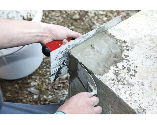 Handwerker glättet mit einer Glättkelle und einer Abziehlatte eine Betonmauer für ein ebenes Ergebnis.