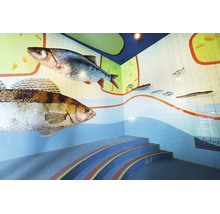 Wandgestaltung mit Mosaikfliesen in Fischoptik und geschwungener Treppe in einem Innenraum.