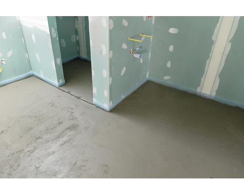 Baustelle mit frisch gegossenem Estrich auf dem Boden und Wänden aus Gipskartonplatten mit verspachtelten Fugen.