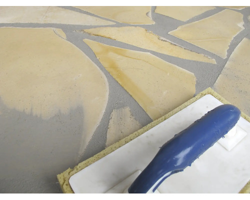 Verfugen von Natursteinplatten im Polygonalverband mit einem Schwammbrett.