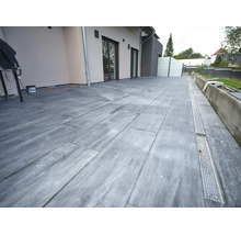 Terrasse mit großformatigen Fliesen in Steinoptik und integrierter Entwässerungsrinne vor einer modernen Hausfassade