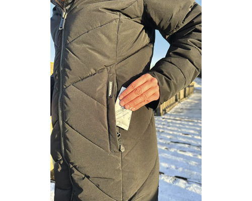 Eine Person trägt eine gesteppte Winterjacke und steckt ein Thermopad Handwärmer Kissen in die Reißverschlusstasche.