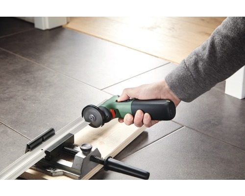 Hand die einen Akku-Multischneider zum Schneiden eines Holzstücks in einer Werkbank verwendet