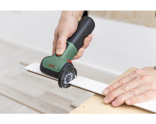 Eine Person schneidet mit einem Multifunktionswerkzeug eine weiße Leiste.