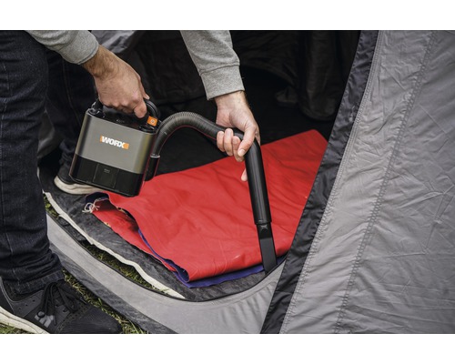 Eine Person benutzt einen WORX Akku-Staubsauger in einem Zelt.