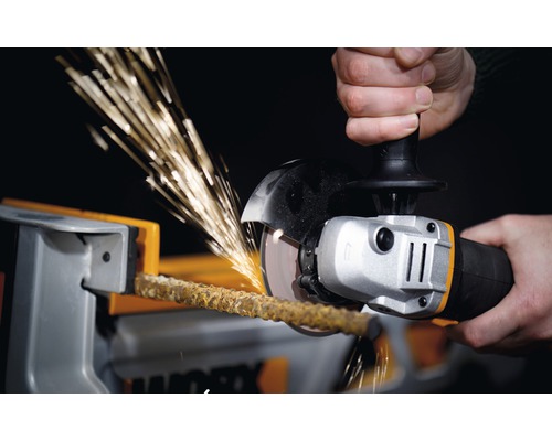 Eine Person schneidet mit einem Winkelschleifer einen Stab in einem Schraubstock, wodurch Funken entstehen.