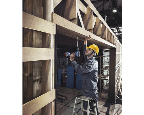 Handwerker bohrt mit Akku-Bohrschrauber ein Loch in eine Holzkonstruktion.