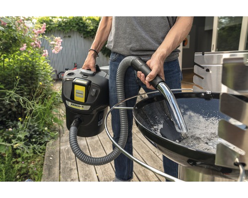 Eine Person reinigt einen Grill mit einem Aschesauger von Kärcher