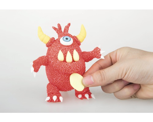 Rotes Monster mit einem Auge, Hörnern und Zähnen wird von einer Hand gehalten