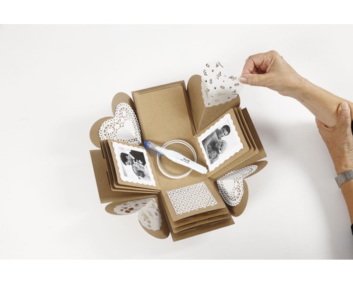 Explosionsbox mit Fotos, Klebestift und Papierdekorationen