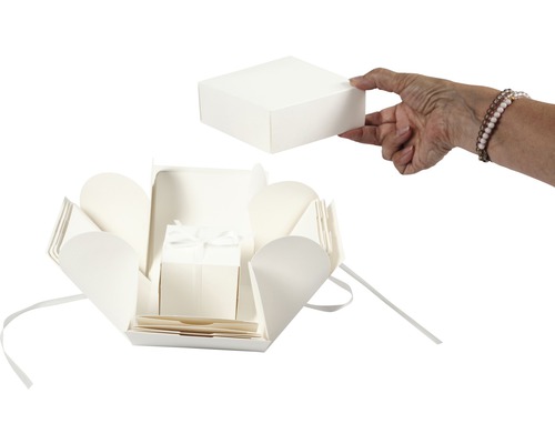 Explosionsbox mit Deckel und Schleife wird von einer Hand gehalten