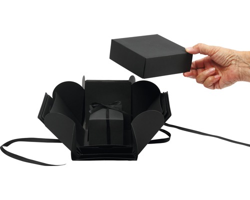 Offene, schwarze Geschenkbox mit Schleife und Deckel, der von einer Hand gehalten wird
