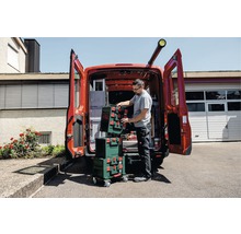 Handwerker verstaut Werkzeugkoffer im Fahrzeug