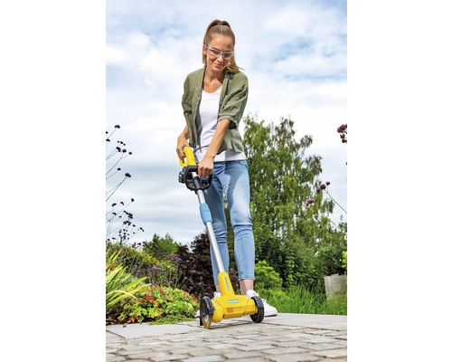 Eine Frau benutzt einen Kantenschneider im Garten.