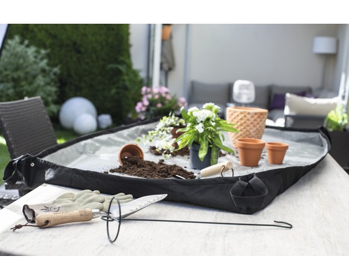Gartenszene mit Pflanzzubehör, Pflanzkasten, Blumenerde und Pflanzen auf einem Tisch