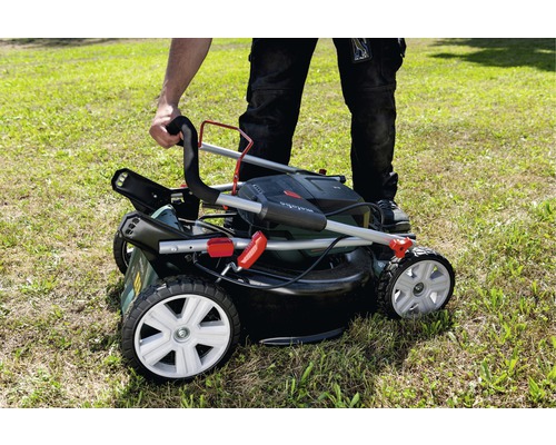 Ein Mann bedient einen Rasenmäher auf einer Rasenfläche.