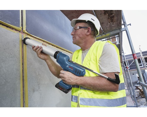 Handwerker verwendet eine Akku-Kartuschenpistole zum Abdichten einer Wand auf einer Baustelle.
