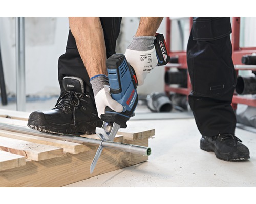 Akkusäge beim Schneiden eines Rohres auf einer Holzkonstruktion.