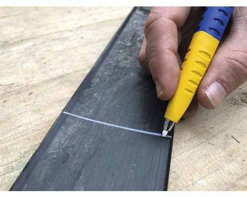 Person zeichnet eine Linie mit einem Stift auf ein Werkstück.