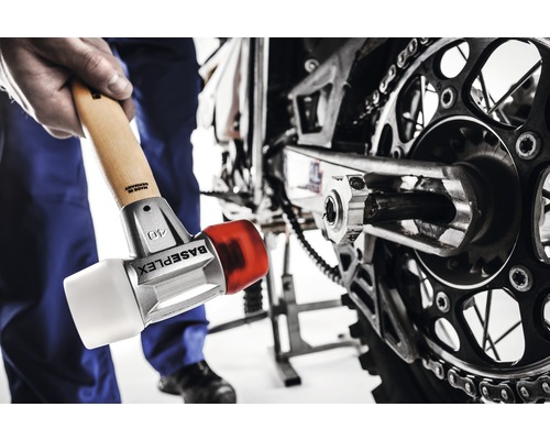 Ein Mann benutzt einen Schonhammer, um an einem Motorrad zu arbeiten.