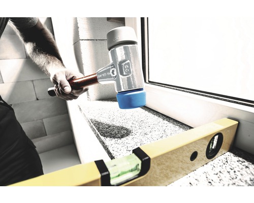 Handwerker arbeitet mit einem Gummihammer und einer Wasserwaage an einem Fensterbrett.