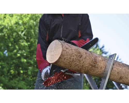 Mann sägt Holzscheit mit einer Kettensäge auf einem Sägebock