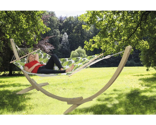 Frau entspannt in einer Hängematte mit Holzgestell und Blattmuster im Garten.