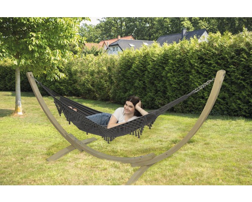 Hängematte mit Holzgestell im Garten mit einer Frau darin.