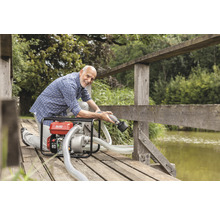 Mann verwendet eine AL-KO Gartenpumpe auf einer Holzbrücke an einem See.