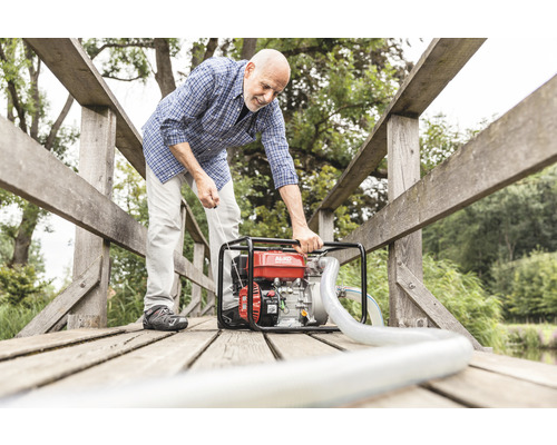 Ein Mann bedient eine Wasserpumpe von AL-KO auf einer Holzbrücke.