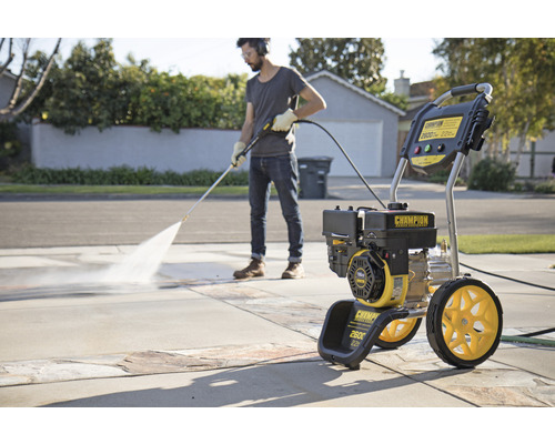 Mann benutzt Hochdruckreiniger zur Reinigung einer Auffahrt. Champion Logo sichtbar.