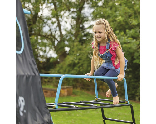 Mädchen klettert auf einem Klettergerüst im Garten.