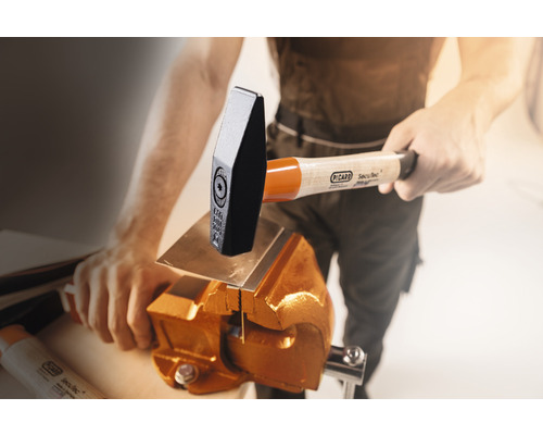 Mann bearbeitet Metall mit einem Hammer und Schraubstock.