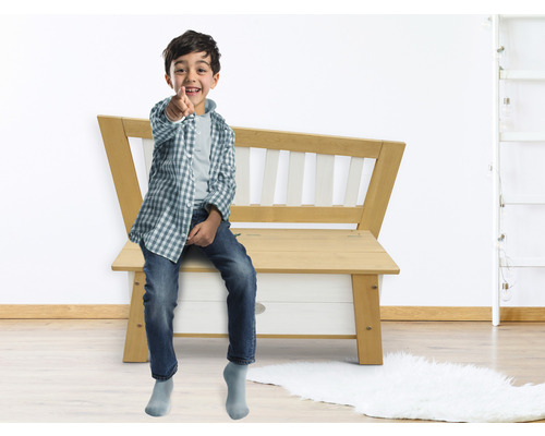 Junge sitzt auf einer Holzbank im Innenbereich