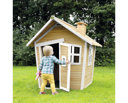 Kind betritt ein Holzspielhaus mit Tür und Fenstern im Garten.