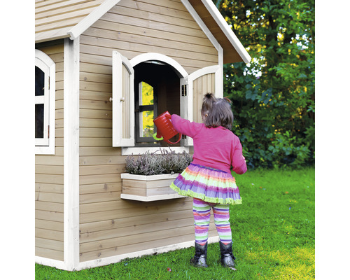Mädchen gießt Blumen vor einem Holzspielhaus im Garten